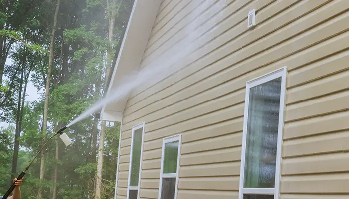Pressure washing siding on a house